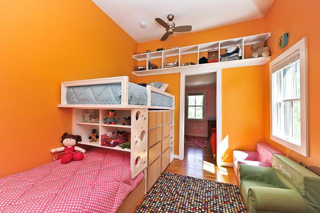 明亮的橙色墙壁用双层床和节省空间的设计为这间女孩房增光.