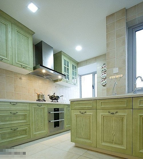 厨房的米色瓷砖色调柔和，整体橱柜采用的是淡青绿色，