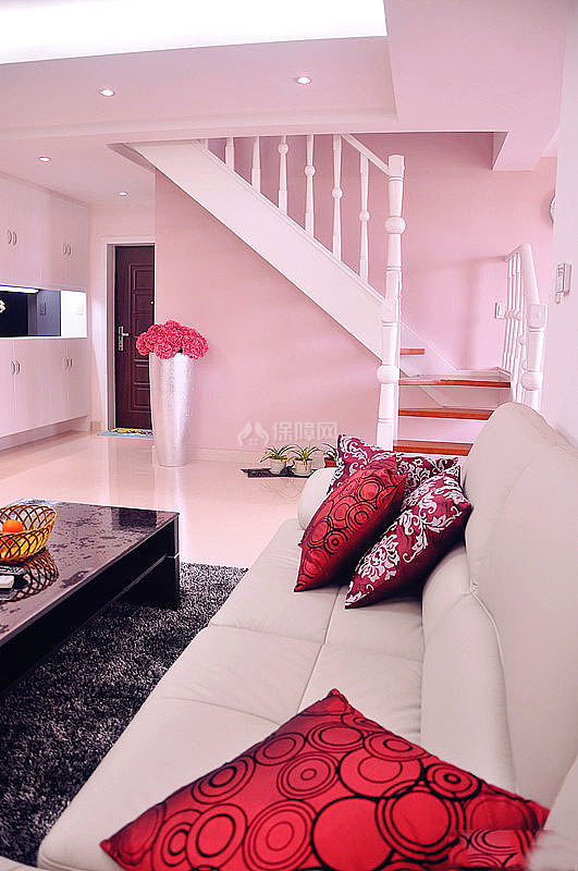 米色的沙发上摆放两三个红色的抱枕，提亮了客厅的颜色