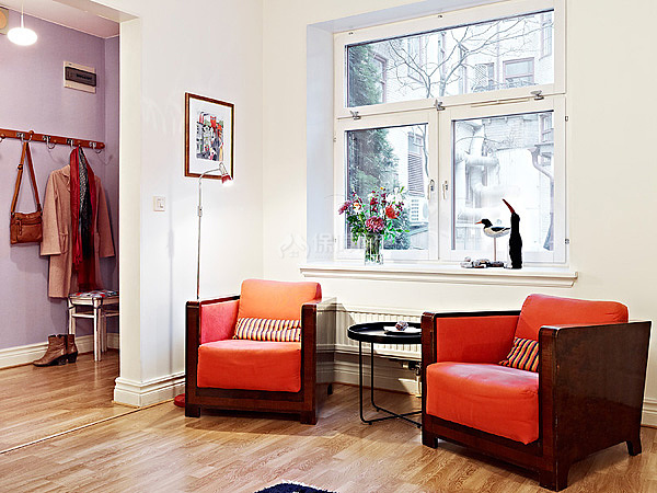 客厅的另一面放着两张橘色沙发，色彩亮丽。